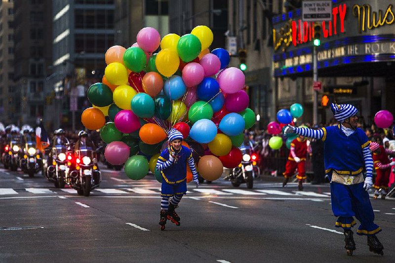 A reveler carries balloons as police on motorcycles cross Sixth Avenue during the Macy’s Thanksgiving Day Parade on Thursday in New York. 