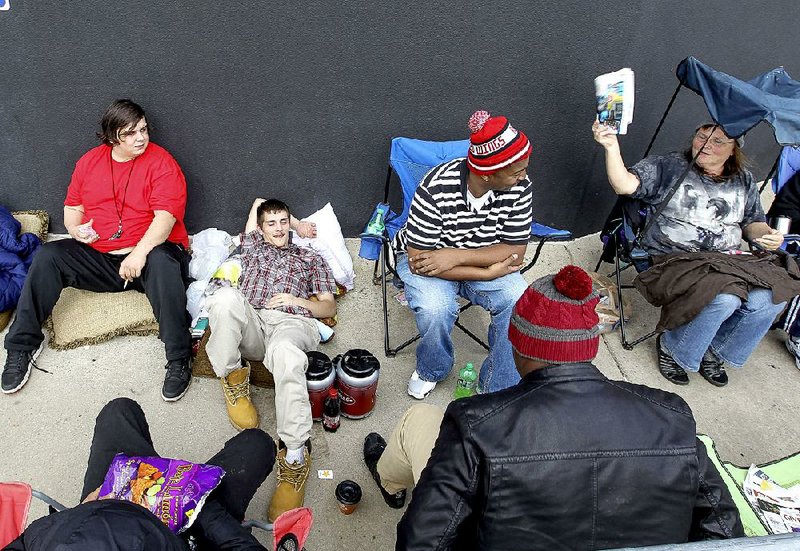 Geneva Vaughn (right) shows a Black Friday deals catalog to Bryant Smith (left) and other shoppers waiting in line for more than 12 hours Thursday to enter the Best Buy store in North Little Rock. 