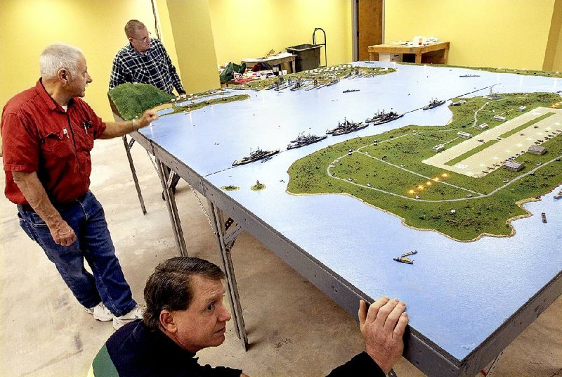 Dix Wood (bottom), Ken MacLeod (left) and Bill Owens work on a model of Pearl Harbor. The men created the diorama based on aerial photos from the day before the Japanese attack.