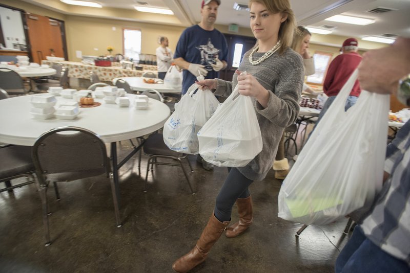 Susanna Luther of Fayetteville carries Thanksgiving meals bound for home delivery Thursday at Farmington United Methodist Church’s first Thanksgiving “Feast-to-Go.” The church prepared around 75 meals for people in need, most of which were picked up, but several were delivered to people who were unable to leave their homes. For more photos, go to www.nwadg.com/photos.
