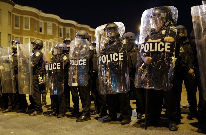 In this April 28, 2015 file photo, police stand in formation as a curfew approache in Baltimore, a day after unrest that occurred following Freddie Gray's funeral. On the campaign trail, among candidates of both parties, the idea of locking up drug criminals for life is a lot less popular than it was a generation ago. 