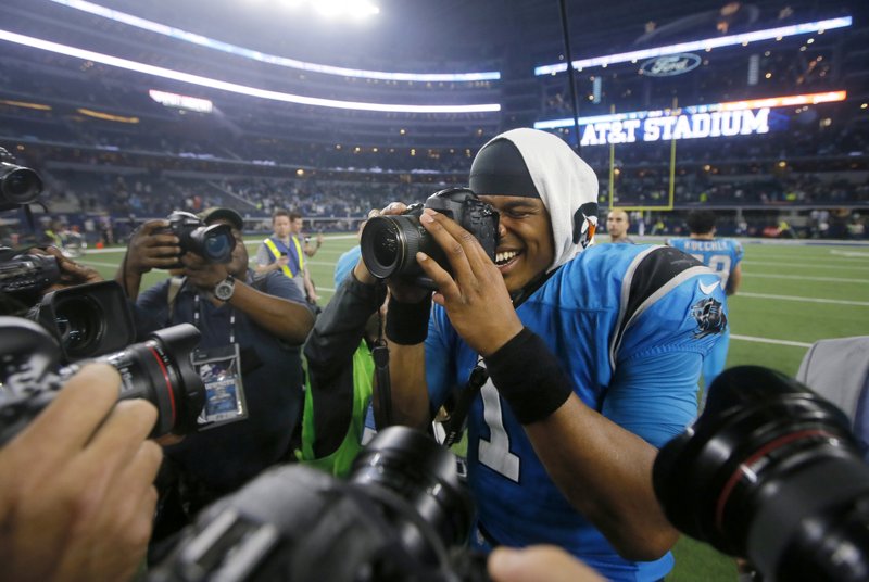 Carolina Panthers quarterback Cam Newton (1) takes photos of photographers taking his picture as he celebrates the team's 33-14 win over the Dallas Cowboys in an NFL football game, Thursday, Nov. 26, 2015, in Arlington, Texas.