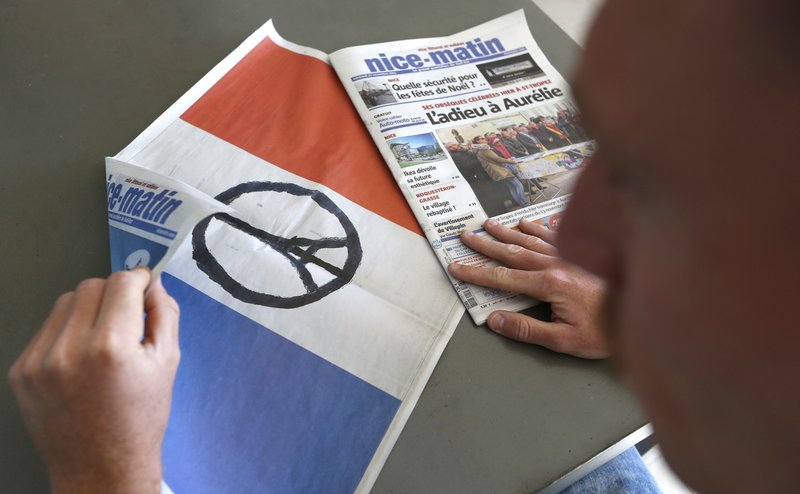 A citizen of Nice holds a French flag printed in the cover of the southeastern France newspaper Nice Matin, Friday, Nov. 27, 2015. French President Francois Hollande called on his compatriots to hang French tricolor flags on Friday to pay homage to the victims of the Nov. 13, attacks, an unusual appeal by a Socialist leader in a country where flag-waving is often associated with nationalists and the far right. (AP Photo/Lionel Cironneau)
