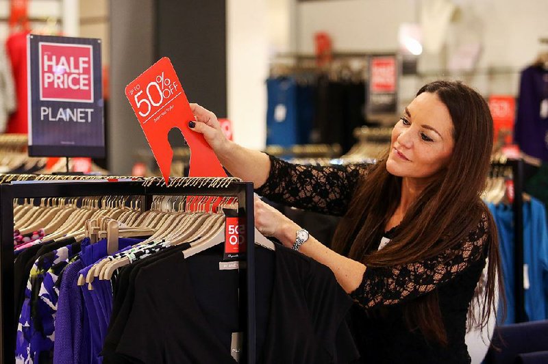 An employee attaches a sign advertising a discount of up to 50 percent inside a Debenhams store on Black Friday in London.