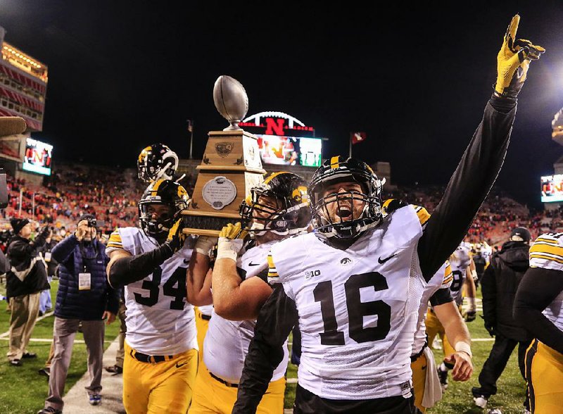 Iowa players, including Nate Meier (34) and Dillon Kidd (16), celebrate with the Heroes Trophy following the No. 4 Hawkeyes’ 28-20 victory over Nebraska on Friday at Memorial Stadium in Lincoln, Neb.