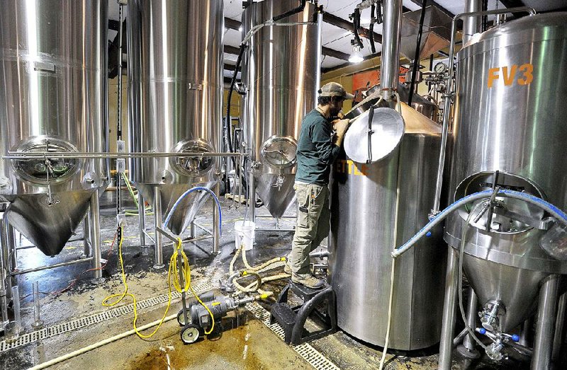 Ben Mills, owner of Fossil Cove Brewery in Fayetteville, checks the tanks of beer.