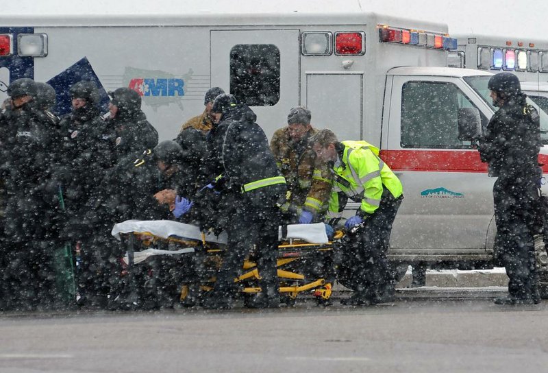 Heavily armed police officers keep watch for a gunman Friday as a wounded comrade is taken to an ambulance near a Planned Parenthood clinic in Colorado Springs, Colo.