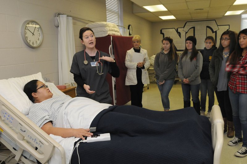 Marvie Landaverde (left), nursing program student, plays the role of a patient Nov. 20 while student Leigh-Anne Pemberton talks to high school students about nursing education opportunities at Northwest Technical Institute in Springdale. For more photos, go to www.nwadg.com/photos. 