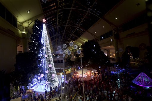 In this Friday, Nov. 27, 2015, photo, people gather to observe a Guinness World Records attempt for the most lights on an artificial Christmas tree in Canberra, Australia.
