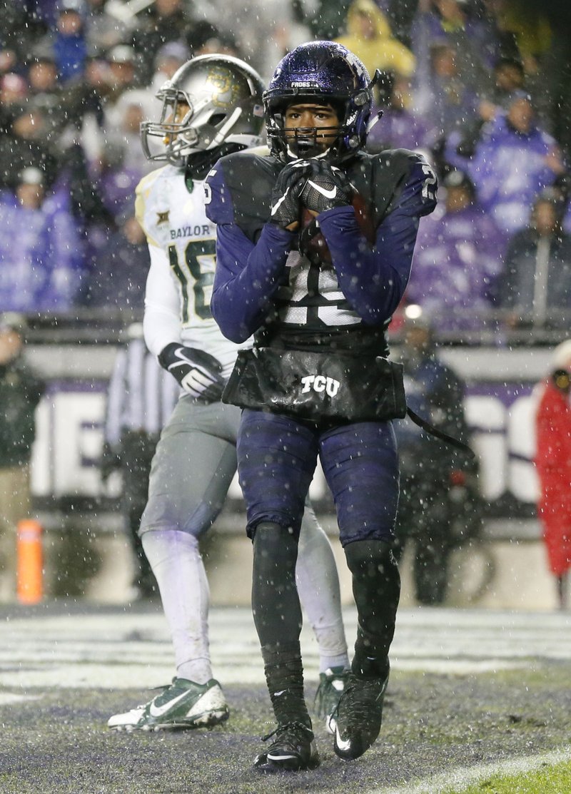 TCU wide receiver KaVontae Turpin (front) holds on tightly for what turned out to be the game-winning touchdown pass in front of Baylor safety Chance Waz during the second overtime in the No. 19 Horned Frogs’ 28-21 victory over the No. 7 Bears on Friday in Fort Worth. 