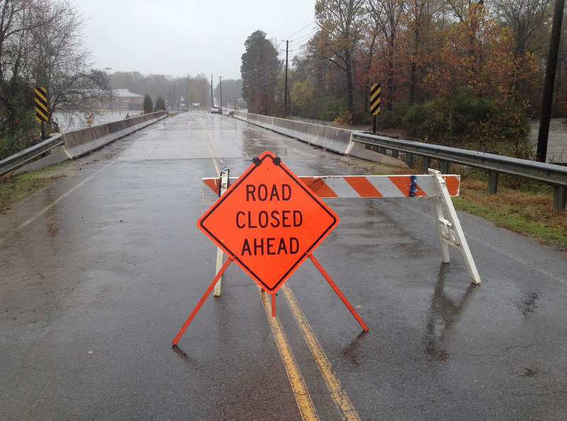 A barricade blocks Boone Road near Bishop Park in Bryant as water crosses the road there Saturday afternoon.
