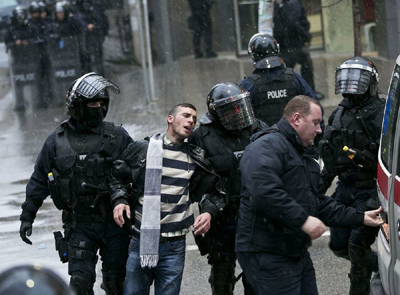 Kosovo police in riot gear detain a man during a raid Saturday at the opposition party headquarters in Pristina. 