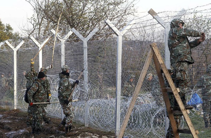Macedonian Army engineers build a fence Saturday on the border with Greece, near the southern Macedonian town of Gevgelija, to curtail migrants. 
