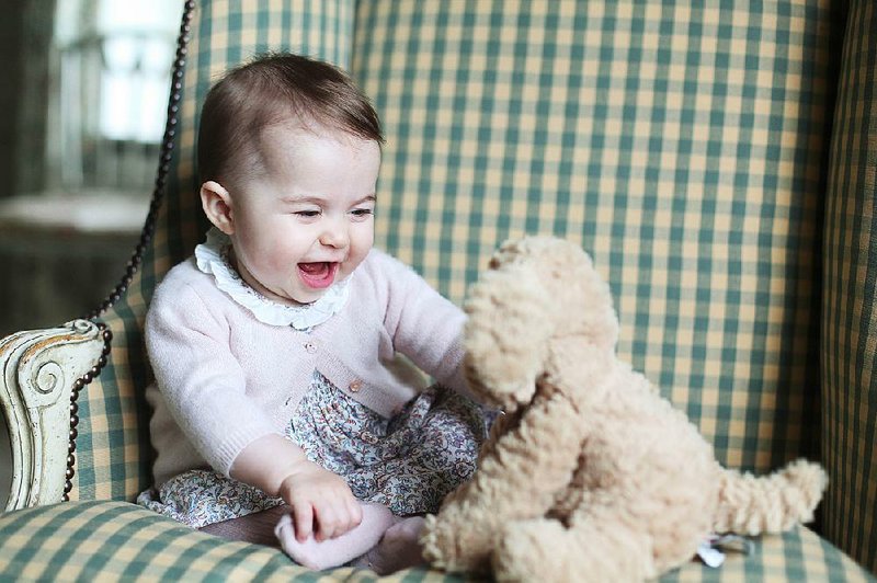 In this undated photo released Sunday Nov. 29, 2015, by Britain's Duke and Duchess of Cambridge, showing Princess Charlotte with her cuddly toy dog, at Anmer Hall in Sandringham, England.  