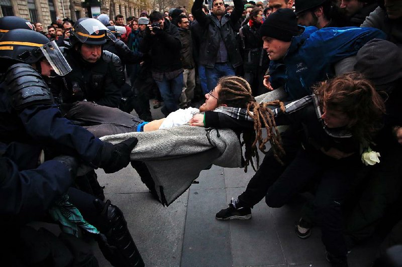 An activist is arrested by riot police Sunday near the Place de la Republique in Paris during a protest ahead of a climate conference.