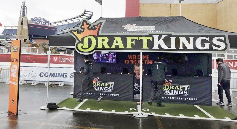 Workers set up a DraftKings promotions tent in the parking lot at Gillette Stadium in Foxborough, Mass., in October. Online companies offering fantasy sports competitions are changing the way they operate as the new industry faces legal scrutiny.