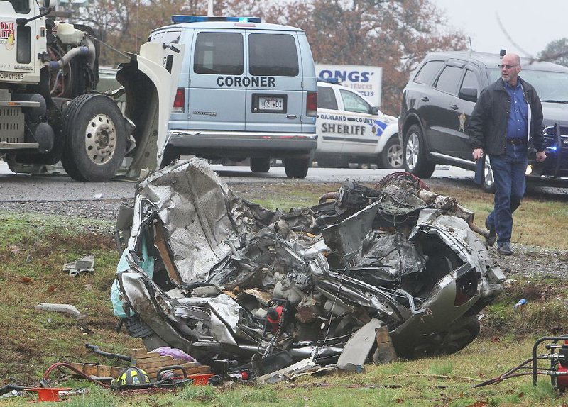 An Arkansas State Police trooper examines the wreckage of an Infi niti sedan that was involved in an accident with an 18-wheeler about 9:30 a.m. Monday in Hot Springs. The woman driving the Infiniti was pronounced dead at the scene.
