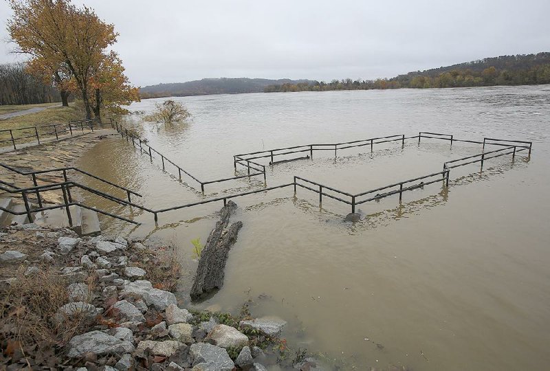 The Arkansas River, which has risen after days of rain, covers the fi shing pier at Burns Park in North Little Rock on Monday afternoon.