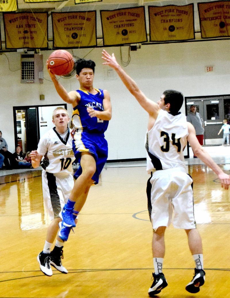 Photo by Mike Eckels Junior guard Leng Lee goes airborne in an attempt to pass the basketball over a West Fork player during the Bulldog-Tiger matchup in the gym at West Fork Nov. 20. Lee&#8217;s pass to Decatur&#8217;s Taylor Haisman resulted in a three-point play.