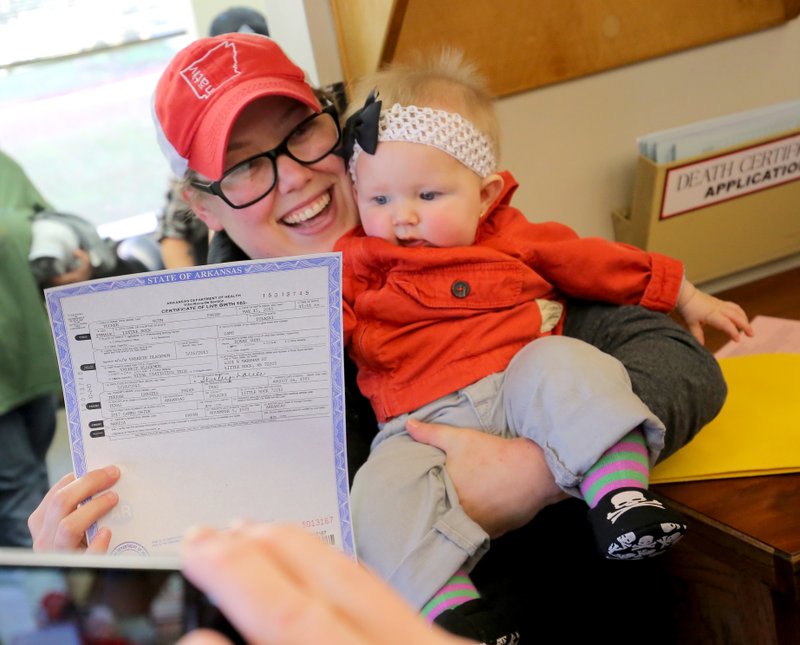 Marisa Pavan, poses Wednesday with daughter Tucker Ruth Pavan, 6 months, and their newly issued amended birth certificate for Tucker Ruth at the Arkansas Vital Records office in Little Rock. Marisa Pavan and wife Terrah Pavan sued to have Marisa’s name added to their daughter’s birth certificate.