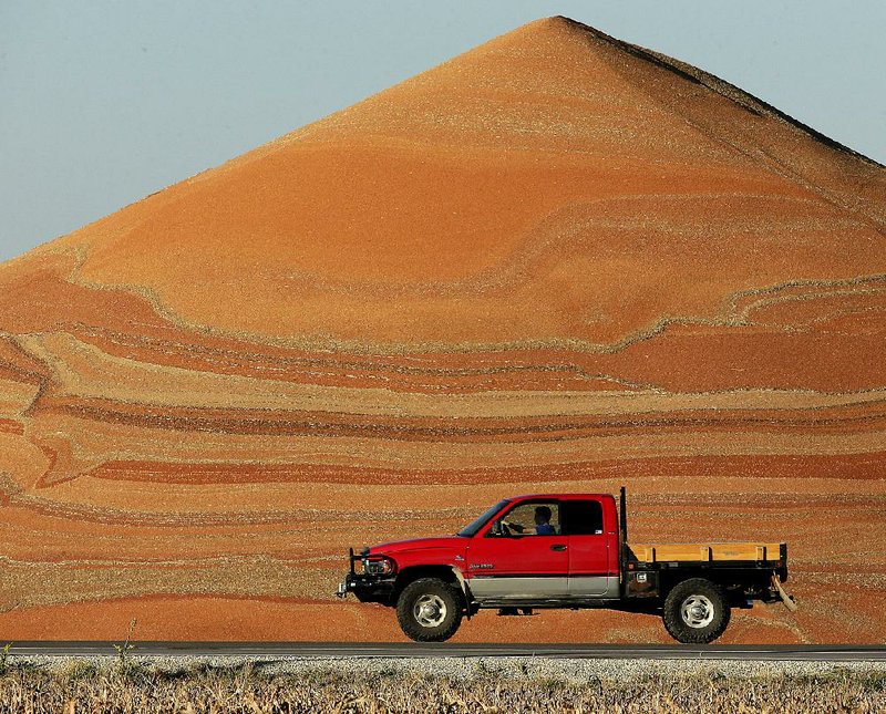 A motorist passes a mountain of milo at a grain storage facility near Canton, Kan., in November.