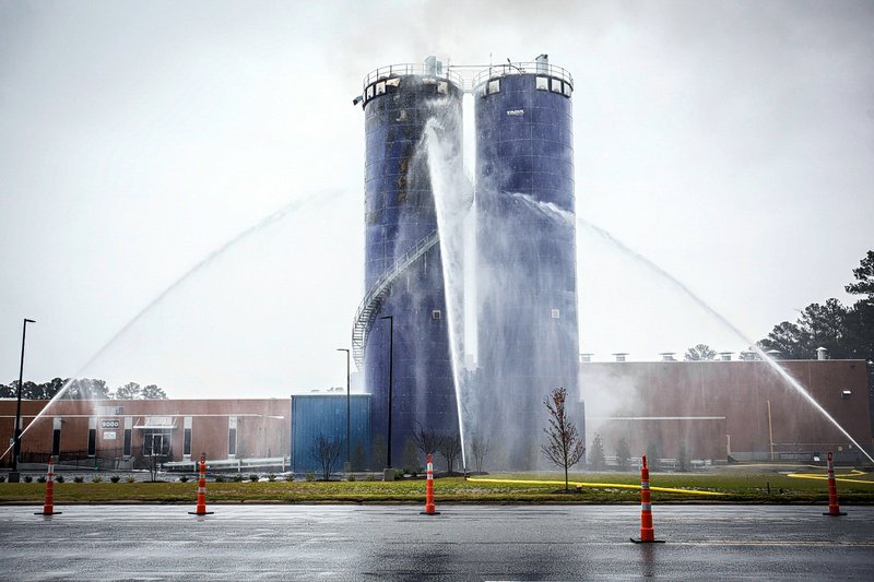 In this photo taken Monday, Dec. 7, 2015, a constant streams of water continues to be applied to a silo fire in Farmville, N.C. The silo full of dehydrated sweet potatoes has been smoldering in the town an hour east of Raleigh since at least the week of Thanksgiving, said Farmville town manager David Hodgkins. (Joe Pellegrino/The Daily Reflector via AP) 
