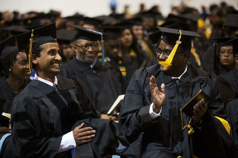 Mohammad Rajib Hasan (right) congratulates Ganesh Karunakaran (left) and other graduates Friday during the University of Arkansas at Pine Bluff commencement. Karunakaran is the first doctoral graduate in UAPB’s aquaculture and fi sheries program. 