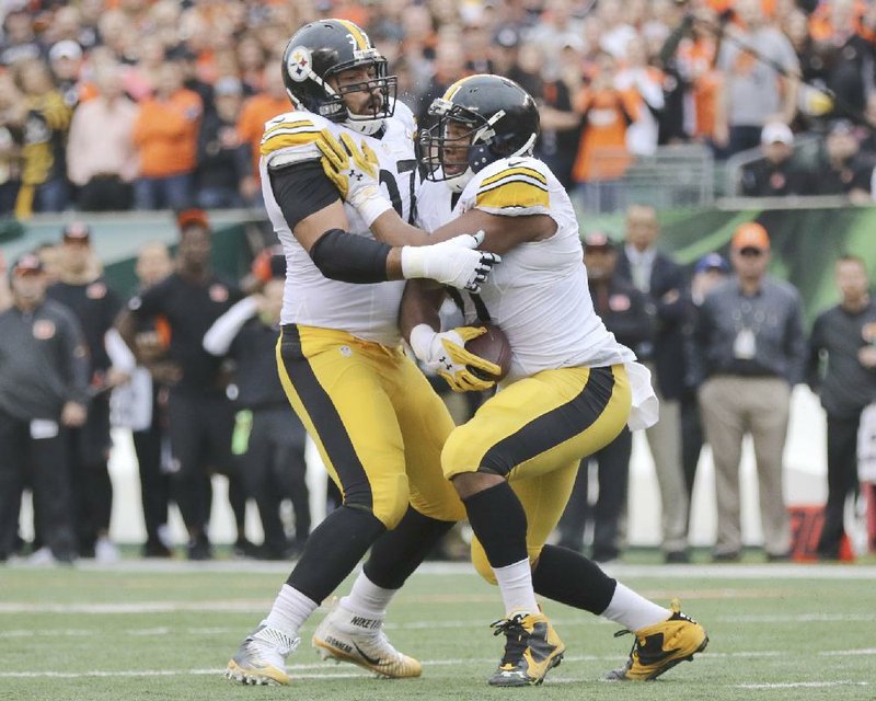 Pittsburgh Steelers defensive end Stephon Tuitt (right) collides with defensive end Cameron Heyward (left) after intercepting a pass from Cincinnati Bengals quarterback Andy Dalton during the fi rst quarter of Sunday’s game in Cincinnati. Dalton broke his right thumb making the tackle on the play.