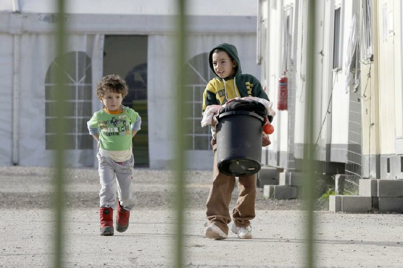 A boy carries a basket of laundry Monday as another child follows him inside Eleonas refugee camp near central Athens, Greece. 