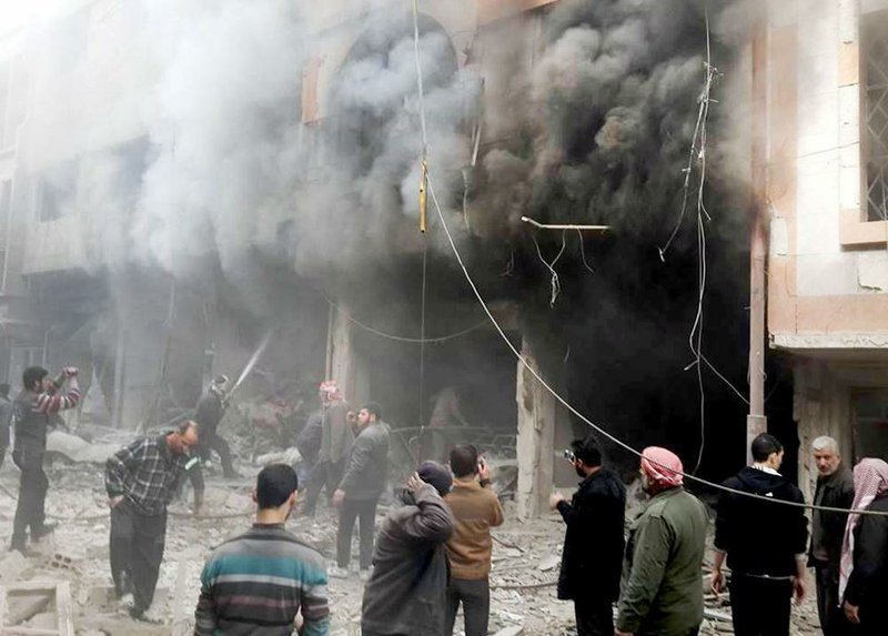 Syrians try to extinguish a fire caused by the Syrian government’s bombardment of the Damascus suburb of Douma on Sunday.