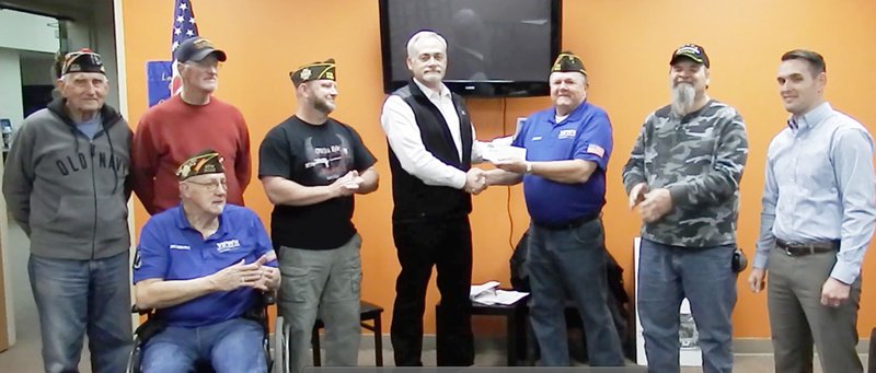 TIMES photograph Mark Howell, center, presented a check for $5,000 to Jerry Burton, commander of the Veterans of Foreign Wars Post 8109, for the Veterans Memorial planned for Pea Ridge. Joining the two were veterans and VFW members Lester Hinton, Kenneth Craig, Howard Schupeltz (seated), Chris Snow Howell, Burton, Jim Parsons and Braxton Hurst. Not pictured: Charlie Brewer.