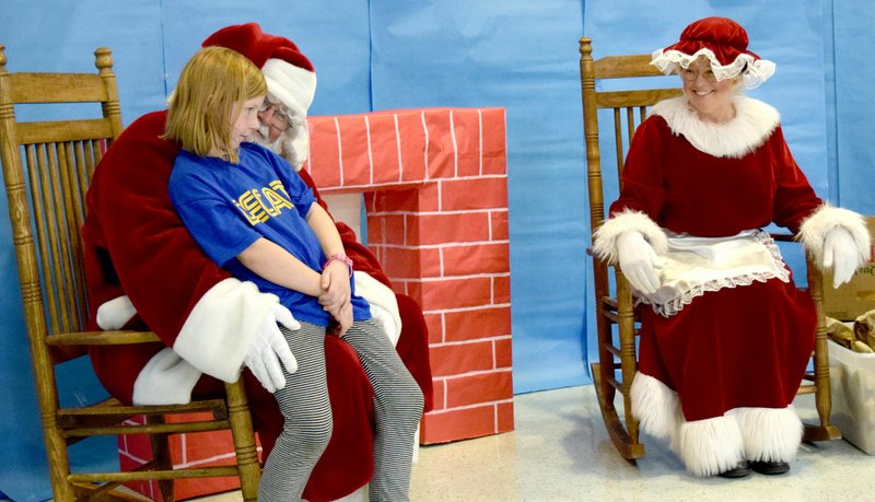 Photo by Mike Eckels Sydnie Brooks gives Santa her Christmas list as Mrs. Clause looks on. The Clauses made their appearance during the Decatur Christmas Festival in the cafeteria at Decatur High School Dec. 12.