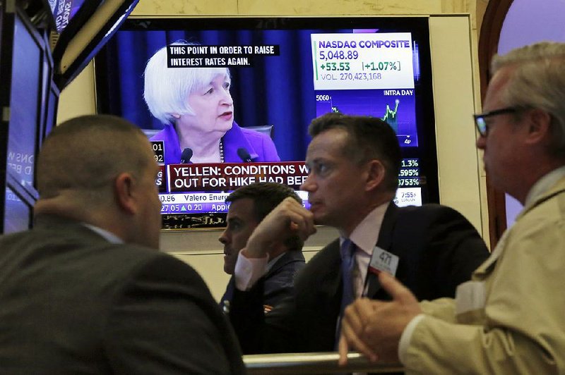 Traders on the floor of the New York Stock Exchange watch Wednesday as Federal Reserve Chairman Janet Yellen holds a televised news conference on the Fed’s decision to raise interest rates. 