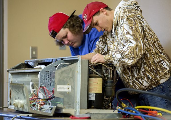Harley Meyers (left) and Dakota Wilmoth, both seniors at Gravette High School, repair a heat exchanger Friday in their HVAC class at the school. The class is taught by Matthew Coleman with Northwest Arkansas Community College.