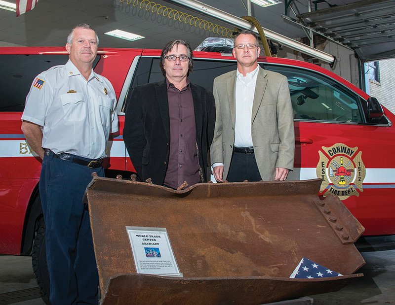 Conway Fire Department Battalion Chief Todd Cardin, left, and Chief Mike Winter, right, stand with Kevin Bass of Conway and a remnant of steel from one of the World Trade Center towers in New York City. Bass saw the piece of steel in the Conway Fire Department and started a GoFundMe page to raise money for a 9/11 Memorial that the department had designed but hasn’t had money to build.
