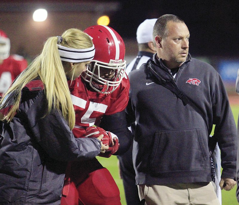 Cabot athletic trainers Jennifer Asberry, left, and Jason Cates guide Cabot football player Dayonte Roberts to the sideline during the second round of the Class 7A state playoffs Nov. 20 at Panther Stadium in Cabot. Cates was hired as Cabot’s first full-time athletic trainer in the spring of 2011.
