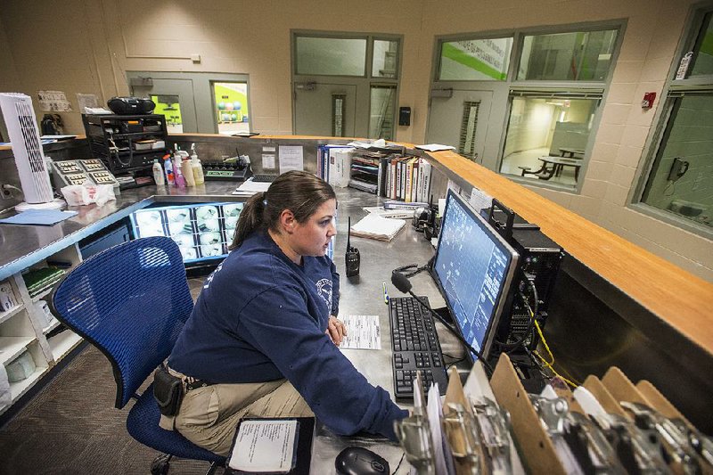 Melissa Frisard, a deputy at the Washington County Juvenile Detention Center, monitors the center’s main work station in Fayetteville. Youths who disobey judges’ orders are housed in juvenile lockups like this one, sometimes winding up alongside those who have raped, robbed or murdered.