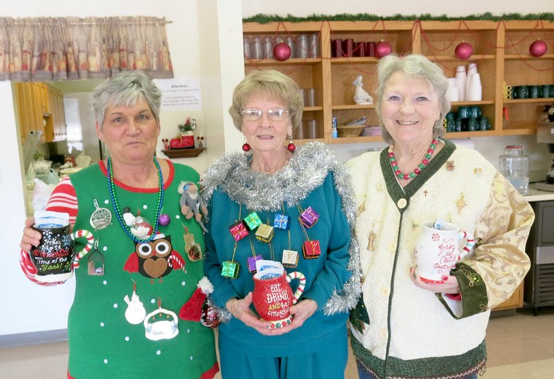 Photo by Susan Holland Guests at the Billy V. Hall Senior Activity and Wellness Center in Gravette participated in an &quot;ugly&quot; sweater competition at their Christmas dinner last Friday. Winners of the contest were, left to right, LaVonda Augustine, first; Juanita Whiteside, second; and Margie Salvatore, third. Each winner received a holiday mug filled with packets of hot chocolate mix and a gift card.