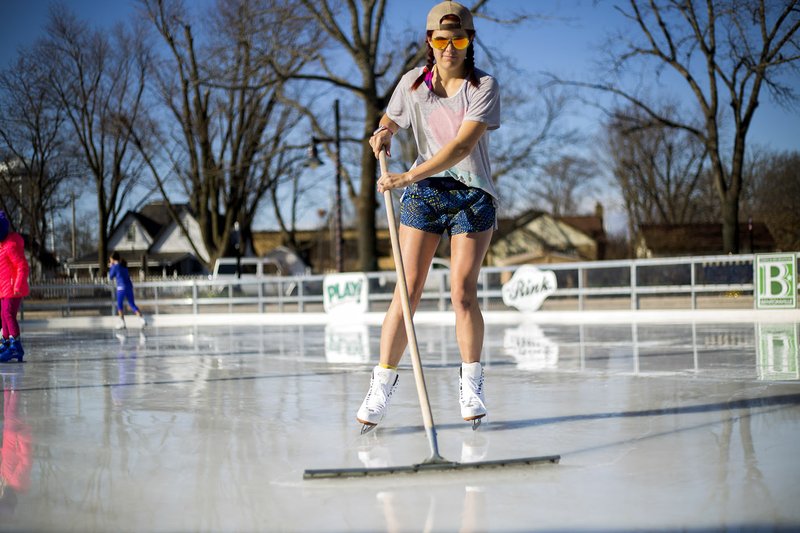 Emily Deal, recreation specialist for Bentonville Parks & Recreation, uses a squeegee to clear water from the surface Monday at the Lawrence Plaza Ice Rink in Bentonville. For more photos, go to www.nwadg.com/photos.
