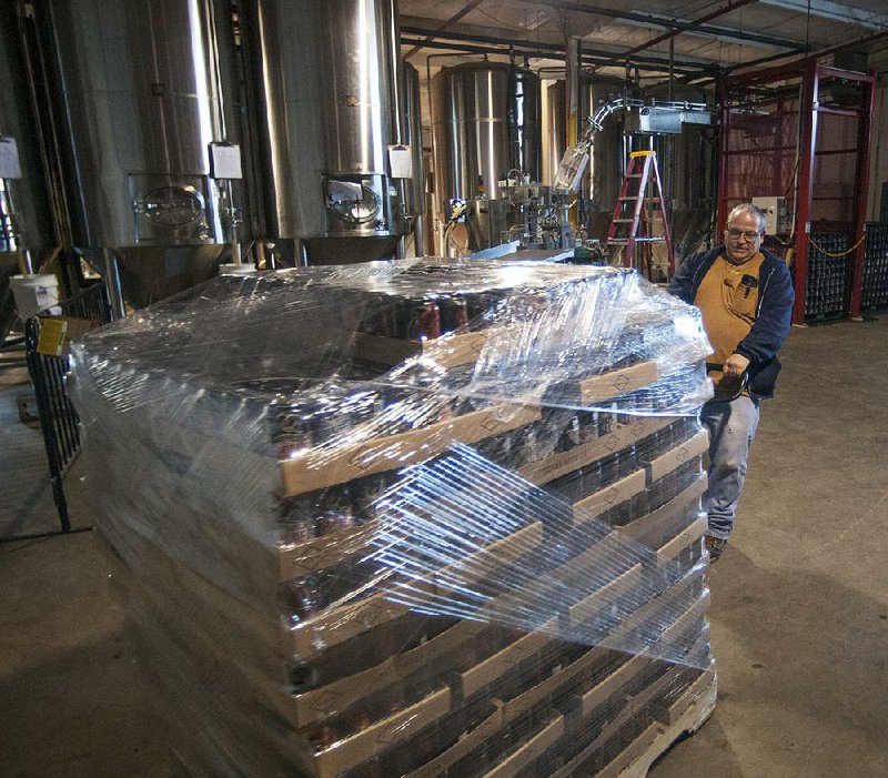 Coby Pistole moves a pallet of beer into place at Ozark Beer Co. in Rogers. The beer-maker has expanded its distribution market to central Arkansas. 