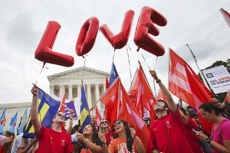 Same-sex marriage supporters hold up balloons that spell the word "love" as they wait outside of the Supreme Court in Washington, Friday June 26, 2015, before the court declared that same-sex couples have a right to marry anywhere in the US.