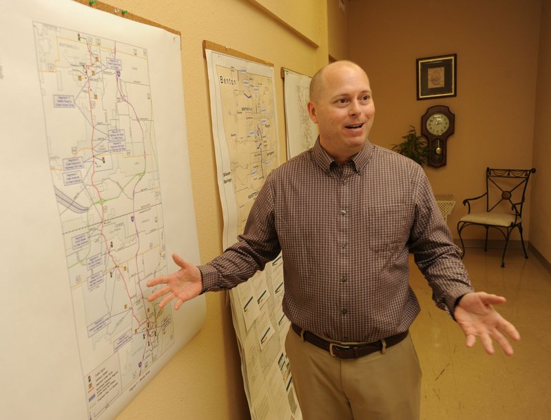 Tim Conklin, transportation programs manager for the Northwest Arkansas Regional Planning Commission, shows off the many maps on his Springdale office walls Dec. 16. Nearly $350 million of highway projects are in the works in Benton and Washington counties, and another $800 million will be needed over the next 25 years, he said. For more photos, go to www. nwadg.com/photos.