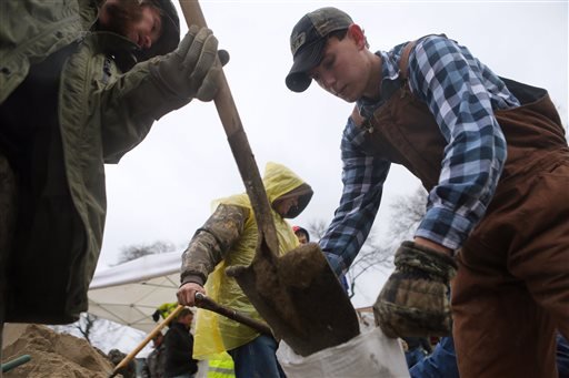 Jesse Nelson, left, 32, of Barnhart, Mo., and Ryan Morris, 20, of Imperial, join other volunteers in making sandbags as the Mississippi River rises after several days of rain in Kimmswick, south of St. Louis on Sunday, Dec. 27, 2015.