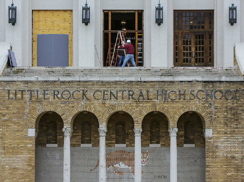 Construction crews remove one of the three sets of doors from the front of Little Rock Central High School on Tuesday morning. Temporary doors (left) will fill in while the original doors undergo renovation in Kansas City, Mo.

