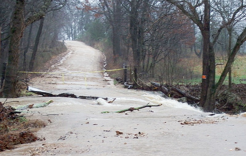 TIMES photographs by Annette Beard Low-water bridges were damaged and were unsafe to cross during the weekend. The county has been declared a disaster by Gov. Asa Hutchinson. County Road Department employees were working on the roads Sunday.