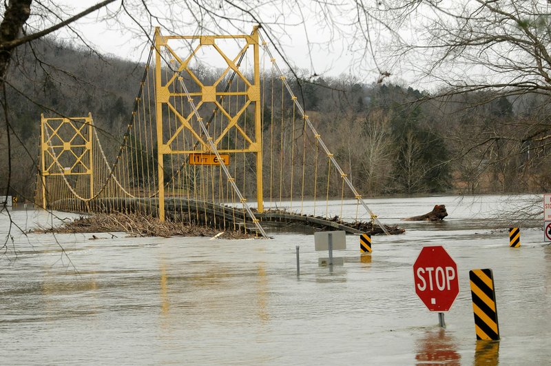 High water tops part of the road Tuesday at the suspension bridge on Arkansas 187 over Table Rock Lake at Beaver in Carroll County. Heavy water releases through the floodgates at Beaver Dam continued Tuesday, but the gates should be closed sometime today, said Alan Bland, park ranger with the Army Corps of Engineers. Barricades and signs informed motorists Tuesday the bridge is closed.