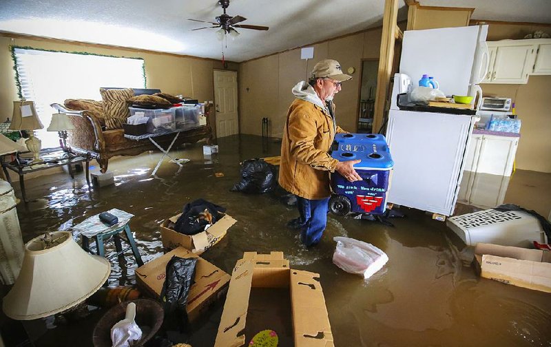 Darryl Turley salvages things from his home Wednesday on Fox Lane in the Toad Suck community near the Arkansas River west of Conway. Turley, who had put some belongings up on cinder blocks, said it was the worst flooding he’d seen in his more than 20 years living in the area. 