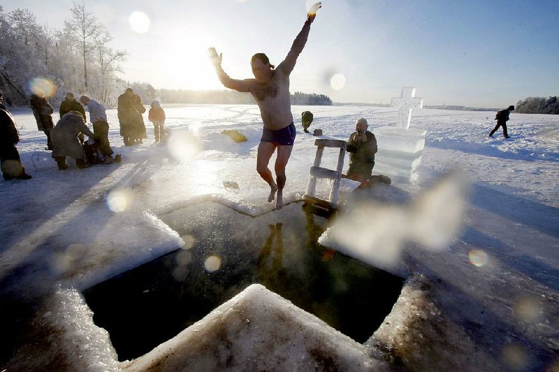 A Russian Orthodox Christian jumps into an ice hole made in the shape of a cross during a traditional Theophany celebration. 