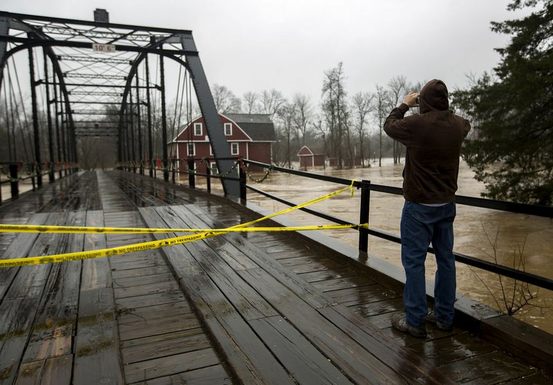 Justin Burkes of Hindsville takes a photo of the overflowing waters in the War Eagle Creek as it reaches the windows of the mill on Monday, Dec. 28, 2015, in Rogers. Traffic was not allowed across the bridge.