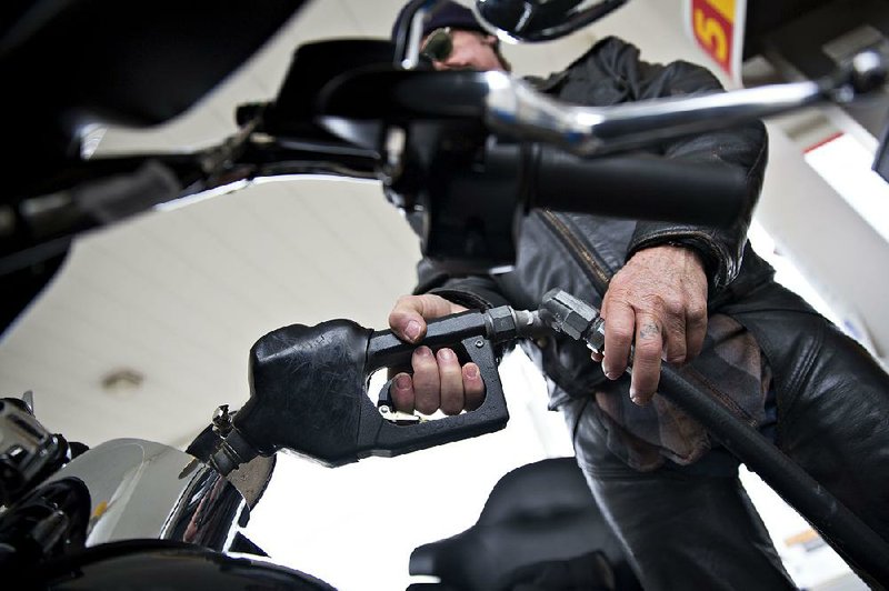 A motorcyclist fills his tank at a gas station in Creve Coeur, Ill., on Dec. 11. Consumers have increased their savings as gasoline prices have dropped, rather than spend the windfall, economists say.